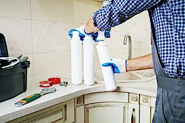 Repairman installing water filter cartridges in a kitchen. Replacing the water filter, water-purification.